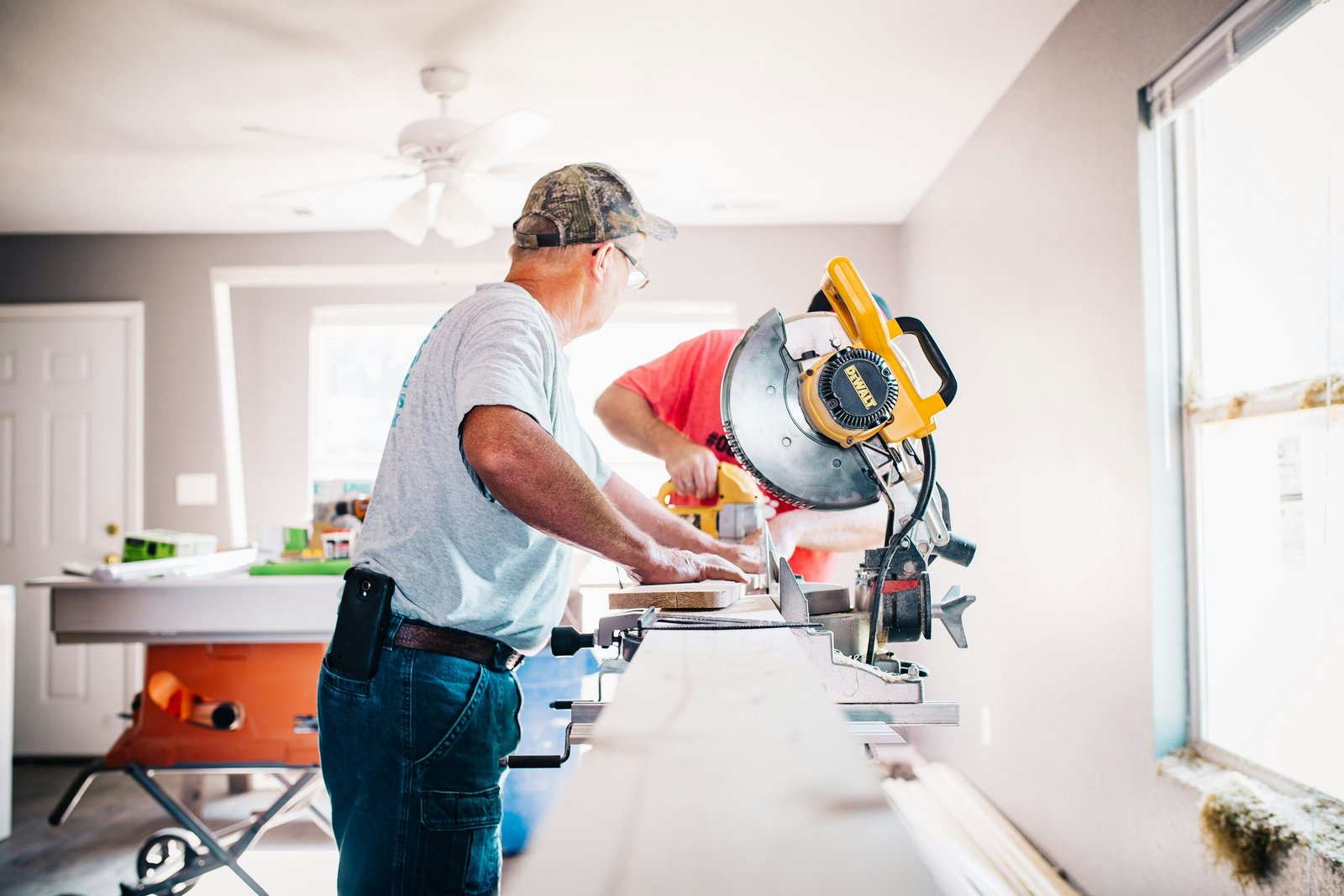 A restoration carpenter working on deck materials at a miter saw