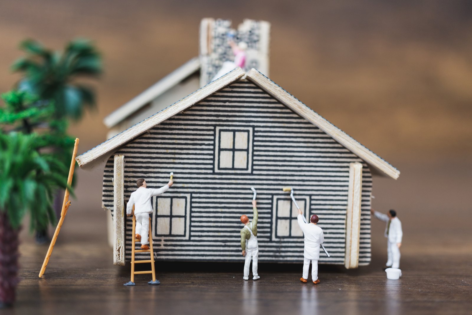 Miniature figures restoring a model house, illustrating residential vs commercial restoration