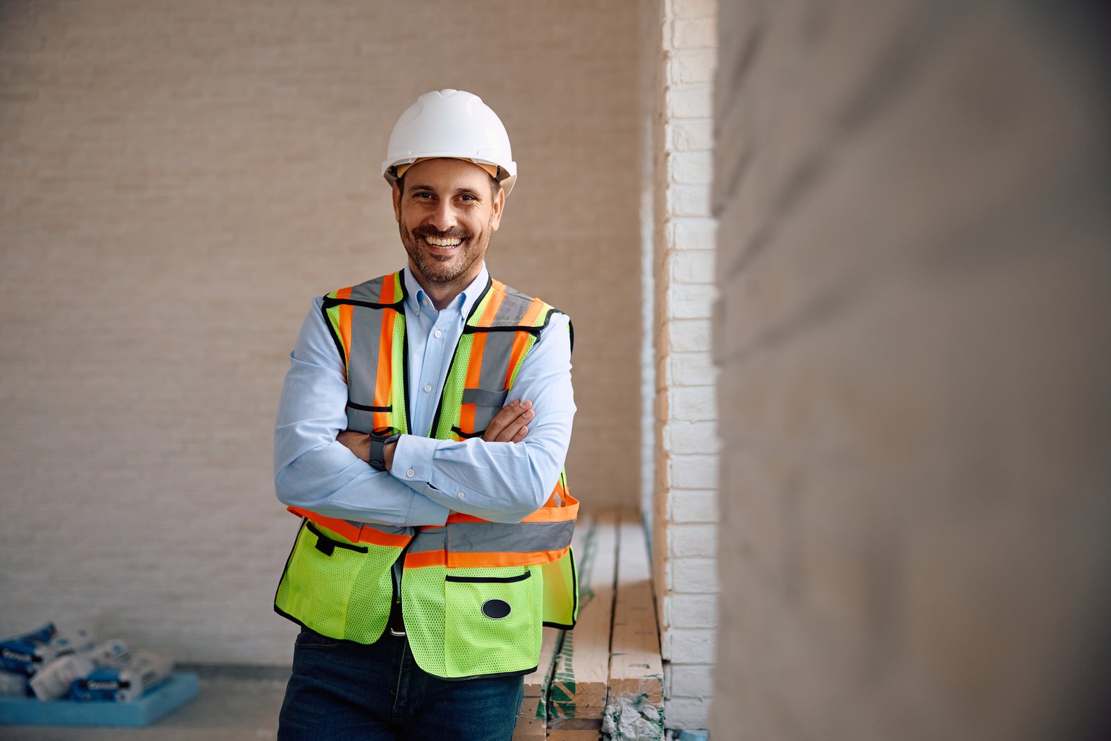 A smiling restoration contractor in a hard hat and hi-vis vest